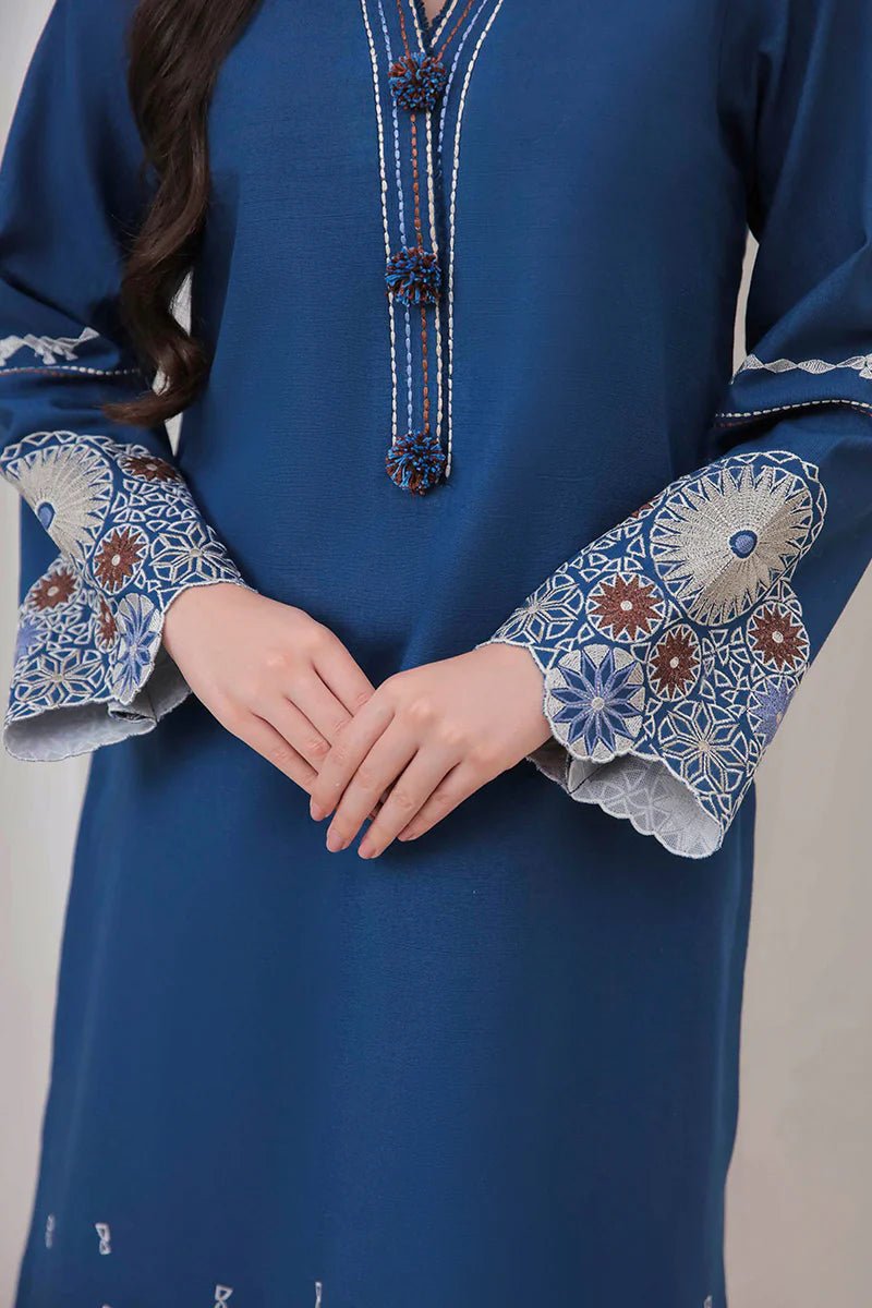 Model wearing Mushq Wisteria Winter Basic Pret '24 Arctic Allure, a deep blue dress with intricate patterns, perfect for winter casual wear. Available for Pakistani clothes online in the UK.