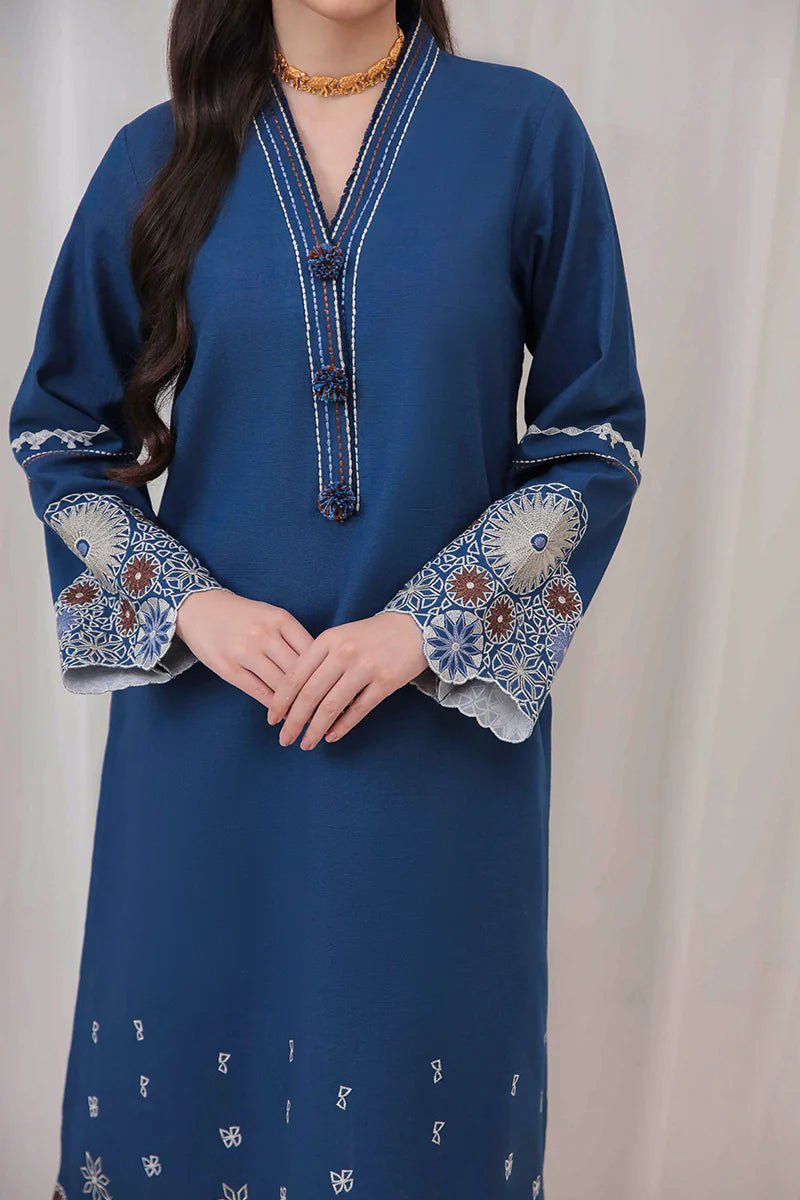 Model wearing Mushq Wisteria Winter Basic Pret '24 Arctic Allure, a deep blue dress with intricate patterns, perfect for winter casual wear. Available for Pakistani clothes online in the UK.