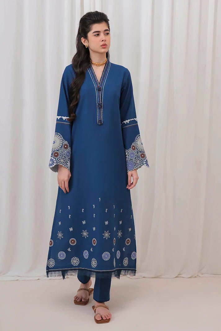 Model wearing Mushq Wisteria Winter Basic Pret '24 Arctic Allure, a deep blue dress with intricate patterns, perfect for winter casual wear. Available for Pakistani clothes online in the UK.