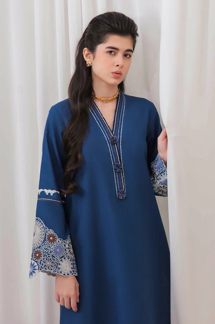 Model wearing Mushq Wisteria Winter Basic Pret '24 Arctic Allure, a deep blue dress with intricate patterns, perfect for winter casual wear. Available for Pakistani clothes online in the UK.