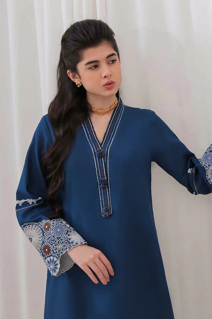 Model wearing Mushq Wisteria Winter Basic Pret '24 Arctic Allure, a deep blue dress with intricate patterns, perfect for winter casual wear. Available for Pakistani clothes online in the UK.