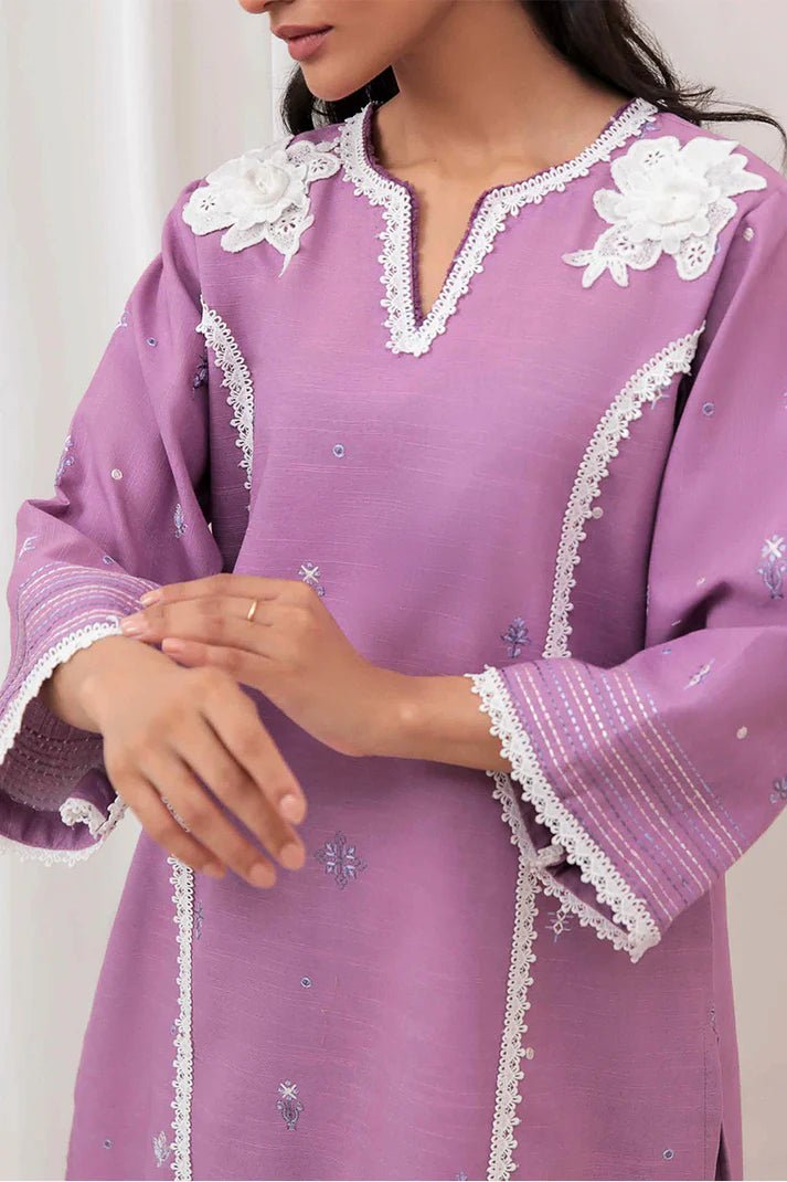 Model wearing Mushq Wisteria Winter Basic Pret '24 Frost Flair, a lavender dress adorned with white lace details, perfect for winter casual wear. Available for Pakistani clothes online in the UK.