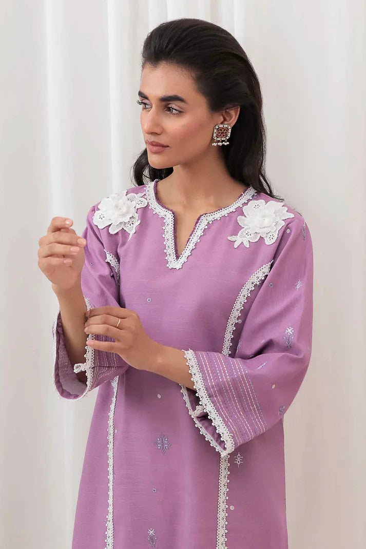 Model wearing Mushq Wisteria Winter Basic Pret '24 Frost Flair, a lavender dress adorned with white lace details, perfect for winter casual wear. Available for Pakistani clothes online in the UK.