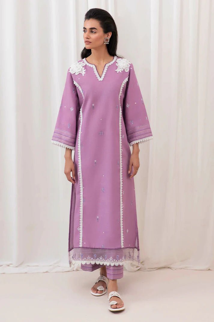 Model wearing Mushq Wisteria Winter Basic Pret '24 Frost Flair, a lavender dress adorned with white lace details, perfect for winter casual wear. Available for Pakistani clothes online in the UK.