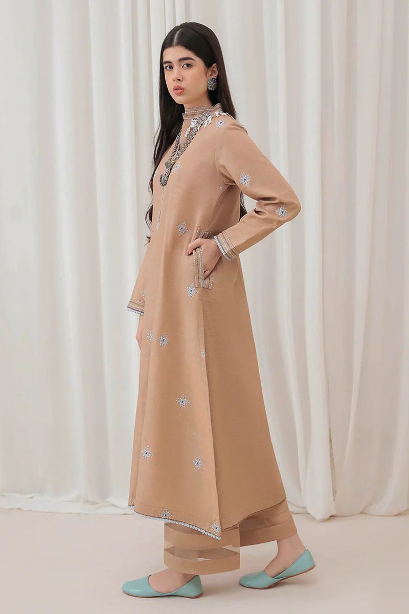 Model wearing Mushq Wisteria Winter Basic Pret '24 Frost Kissed, a beige dress with subtle blue embroidery, ideal for winter casual wear. Available for Pakistani clothes online in the UK.