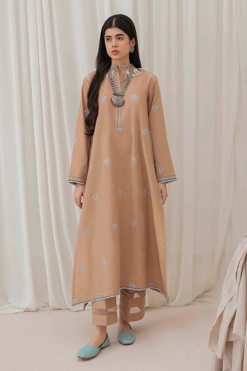 Model wearing Mushq Wisteria Winter Basic Pret '24 Frost Kissed, a beige dress with subtle blue embroidery, ideal for winter casual wear. Available for Pakistani clothes online in the UK.