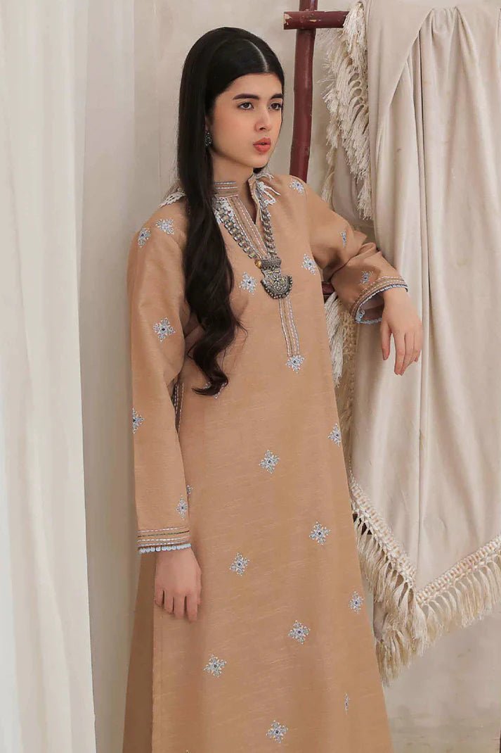 Model wearing Mushq Wisteria Winter Basic Pret '24 Frost Kissed, a beige dress with subtle blue embroidery, ideal for winter casual wear. Available for Pakistani clothes online in the UK.