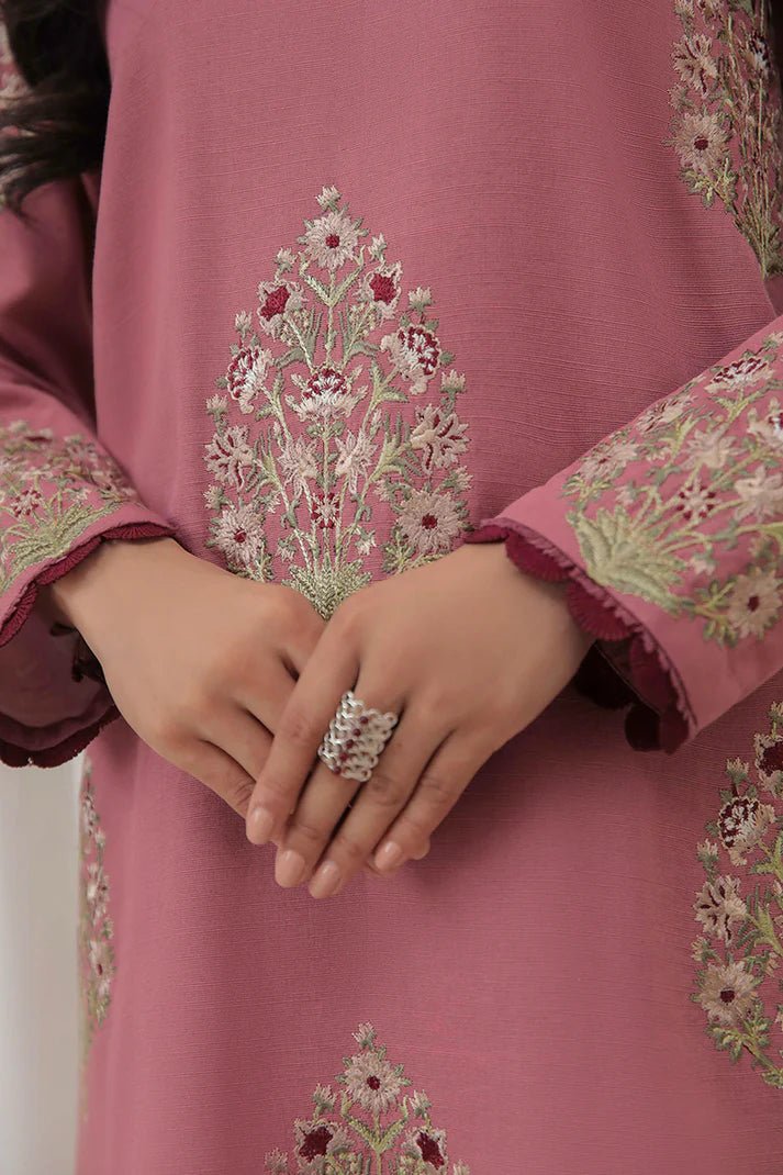 Model wearing Mushq Wisteria Winter Basic Pret '24 Polar Vogue, a rose pink dress with intricate embroidery, ideal for winter casual wear. Available for Pakistani clothes online in the UK.