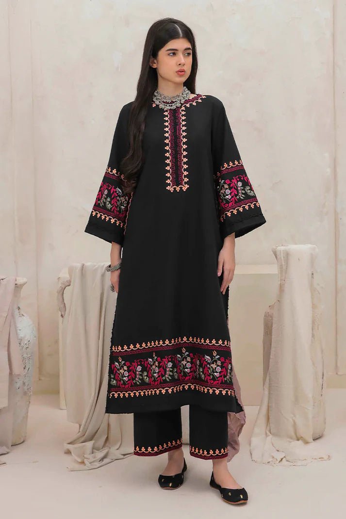 Model wearing Mushq Wisteria Winter Basic Pret '24 Whispering Winds, a black dress with vibrant floral embroidery, ideal for winter casual wear. Available for Pakistani clothes online in the UK.