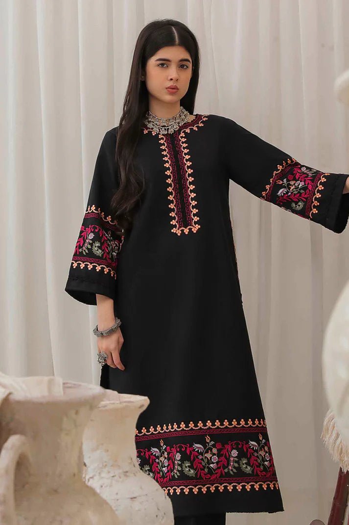 Model wearing Mushq Wisteria Winter Basic Pret '24 Whispering Winds, a black dress with vibrant floral embroidery, ideal for winter casual wear. Available for Pakistani clothes online in the UK.