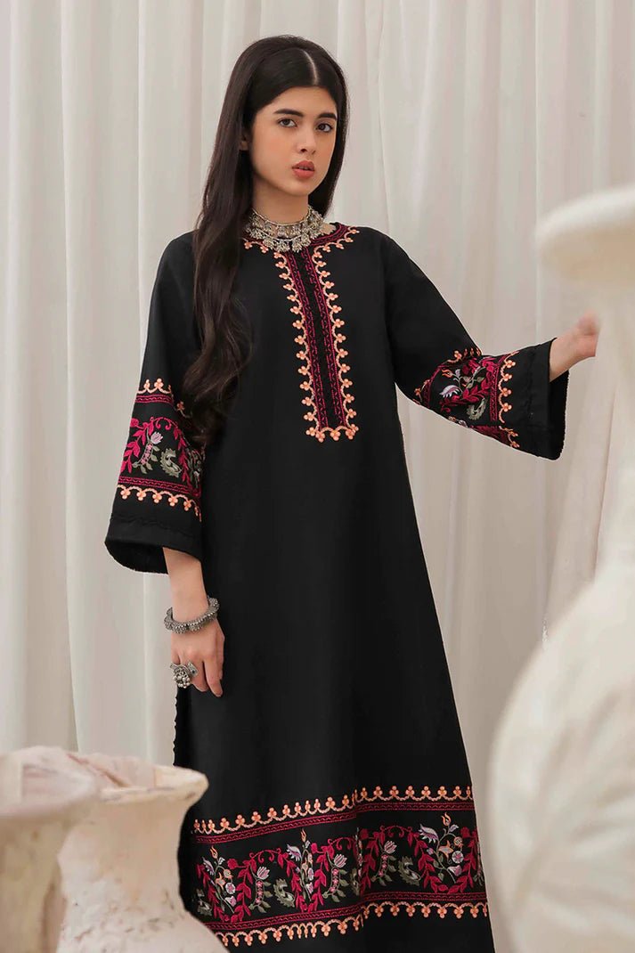 Model wearing Mushq Wisteria Winter Basic Pret '24 Whispering Winds, a black dress with vibrant floral embroidery, ideal for winter casual wear. Available for Pakistani clothes online in the UK.