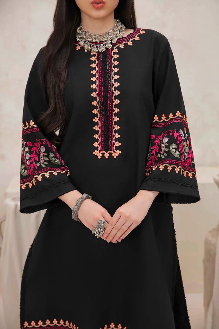 Model wearing Mushq Wisteria Winter Basic Pret '24 Whispering Winds, a black dress with vibrant floral embroidery, ideal for winter casual wear. Available for Pakistani clothes online in the UK.