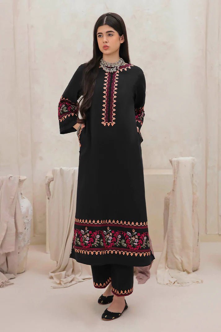 Model wearing Mushq Wisteria Winter Basic Pret '24 Whispering Winds, a black dress with vibrant floral embroidery, ideal for winter casual wear. Available for Pakistani clothes online in the UK.