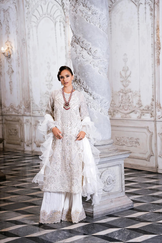 Model wearing SUZANNA ivory dress from Mysie by Tahira, featuring intricate silver embroidery and ruffled sleeves. Ideal for weddings. Find Pakistani clothes online in UK.