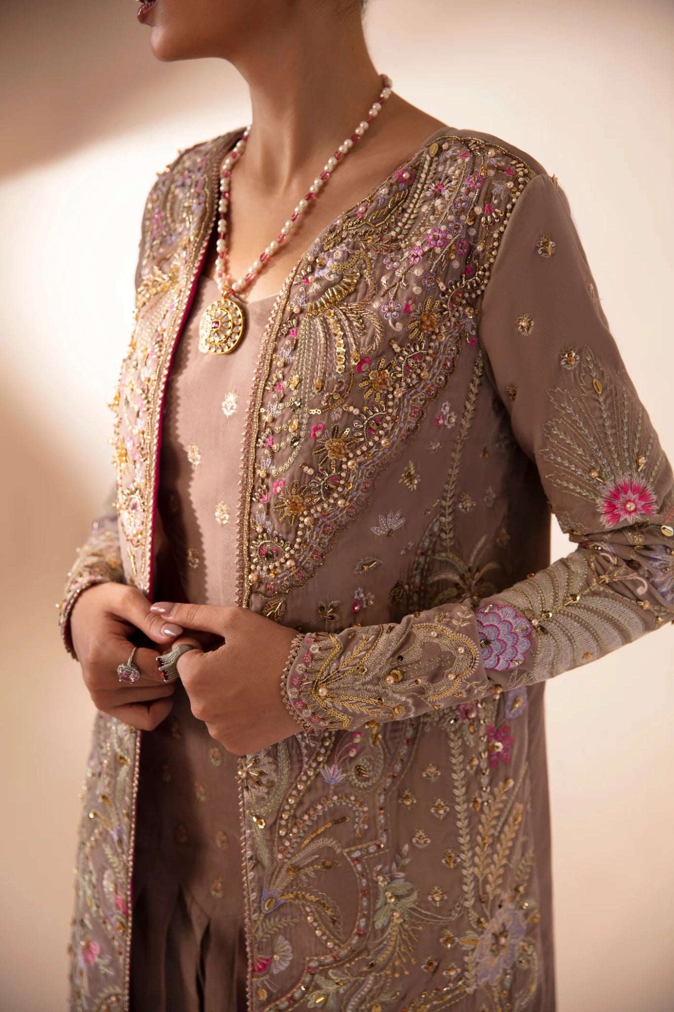 Model wearing FA'IA from Mysie by Tahira in taupe, featuring a pleated skirt and embellished jacket. Pakistani clothes online in UK, ideal for weddings and formal occasions.