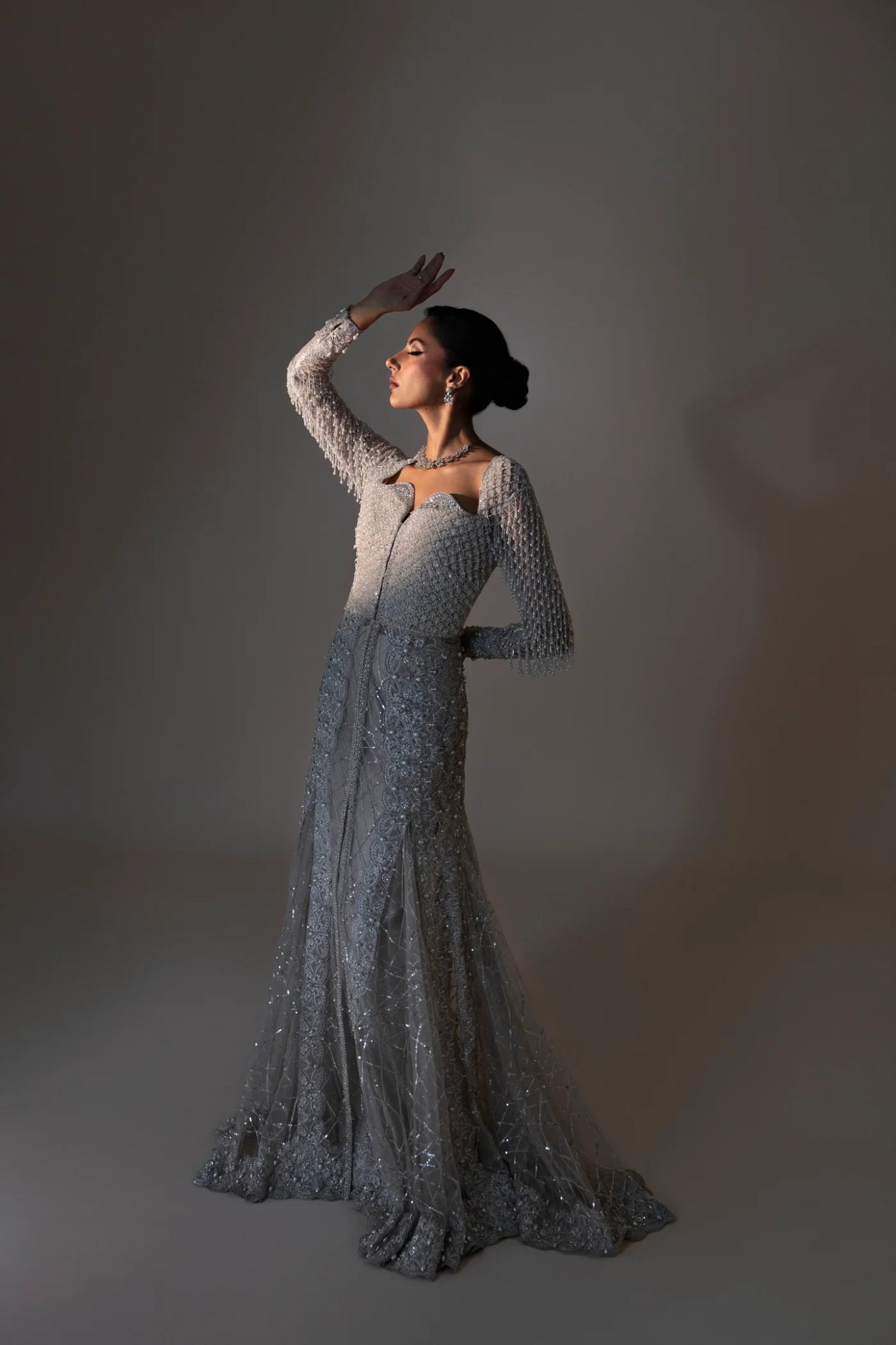 Model wearing Ferē from Mysie by Tahira in a silver embellished gown with long sleeves. Pakistani wedding clothes online in UK, perfect for formal events.