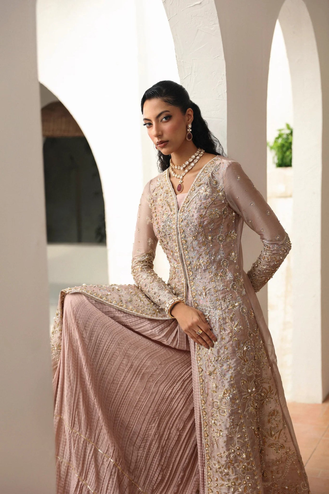 Model wearing Yara from Mysie by Tahira in a blush pink heavily embellished formal dress with pleated lehenga. Pakistani wedding clothes online in UK.