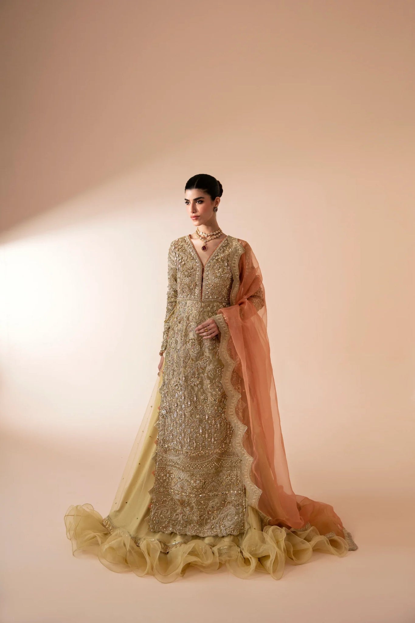 Model wearing Aram from Mysie by Tahira in a gold embellished bridal dress with a peach dupatta. Pakistani wedding clothes online in UK.