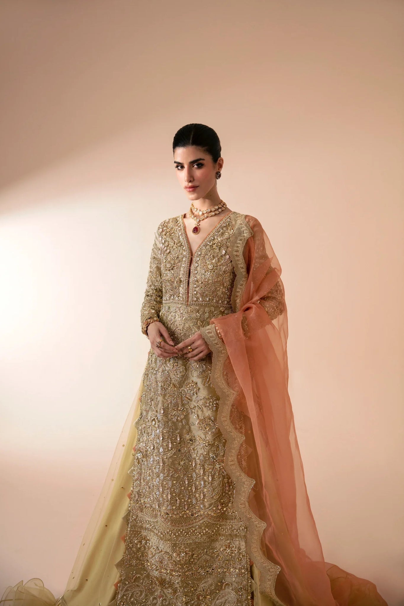 Model wearing Aram from Mysie by Tahira in a gold embellished bridal dress with a peach dupatta. Pakistani wedding clothes online in UK.