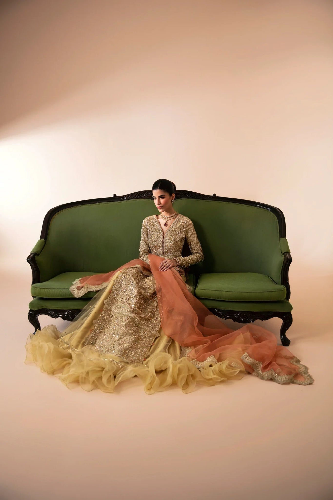 Model wearing Aram from Mysie by Tahira in a gold embellished bridal dress with a peach dupatta. Pakistani wedding clothes online in UK.