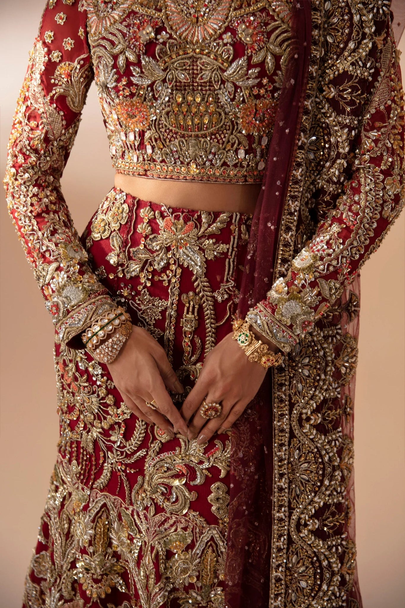 Model wearing Leela from Mysie by Tahira in a red and gold heavily embellished bridal lehenga. Pakistani wedding clothes online in UK.