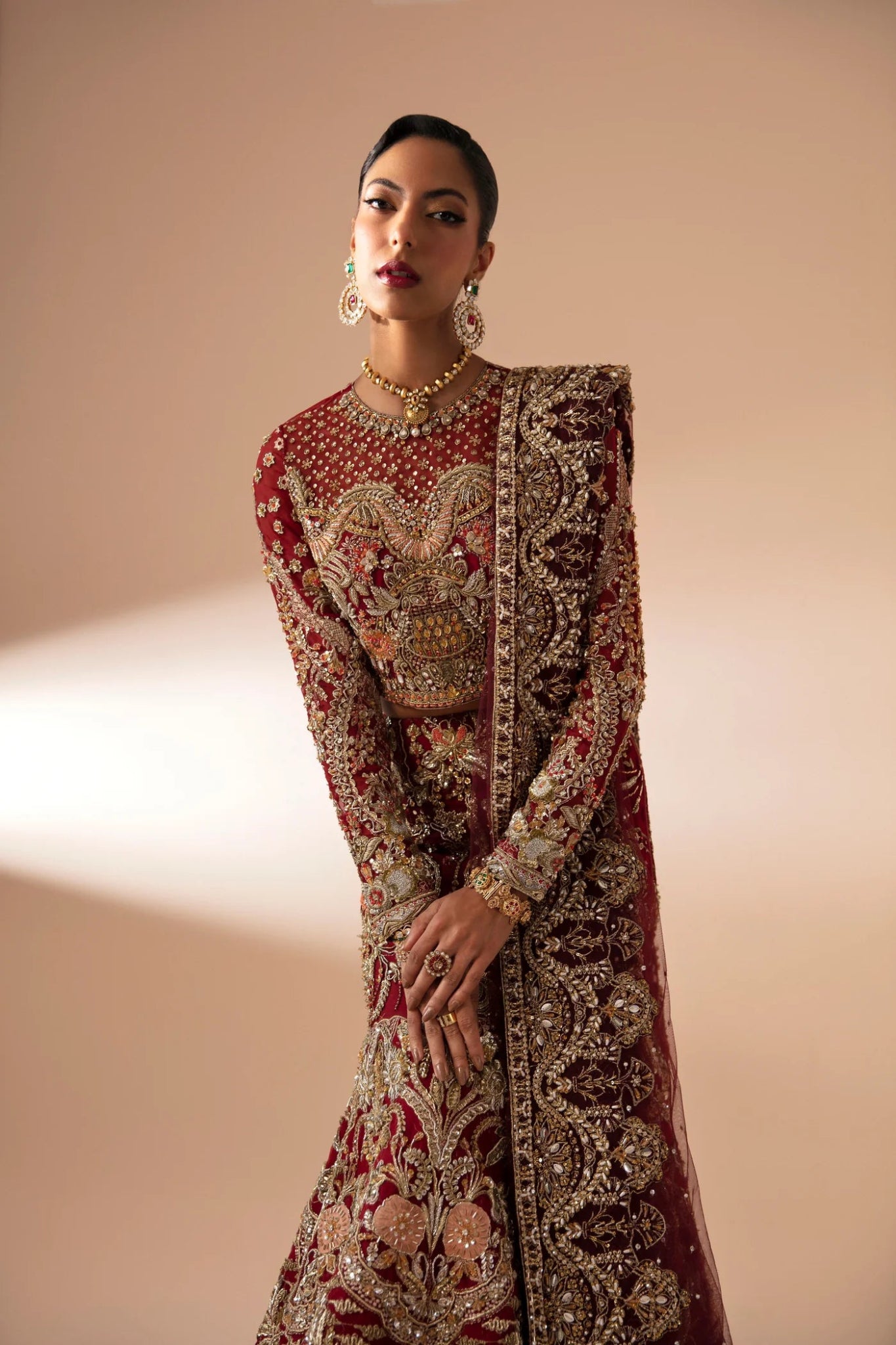 Model wearing Leela from Mysie by Tahira in a red and gold heavily embellished bridal lehenga. Pakistani wedding clothes online in UK.