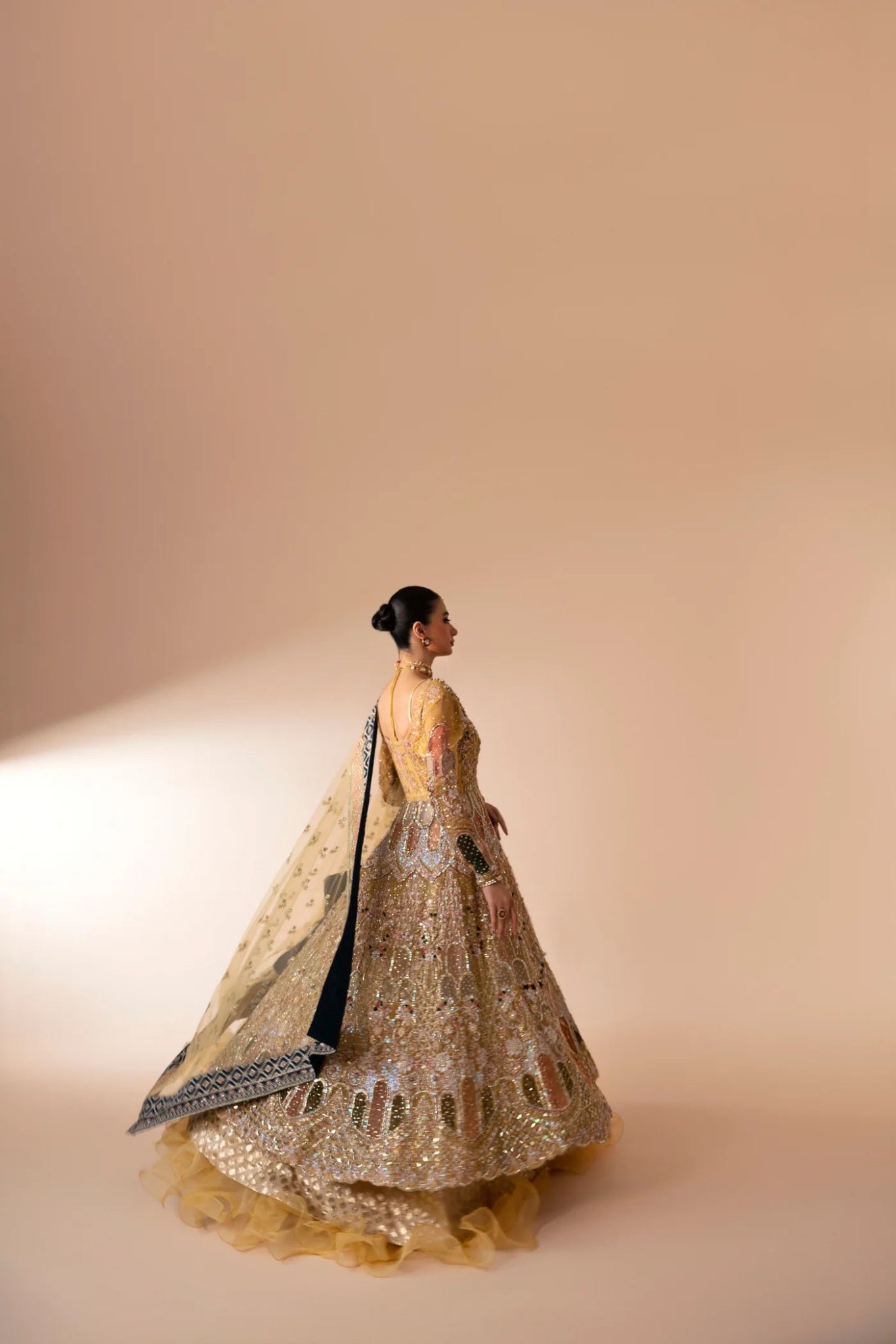 Model wearing Manara from Mysie by Tahira in a gold embellished bridal dress with intricate detailing and multi - colored accents. Pakistani wedding clothes online in UK.