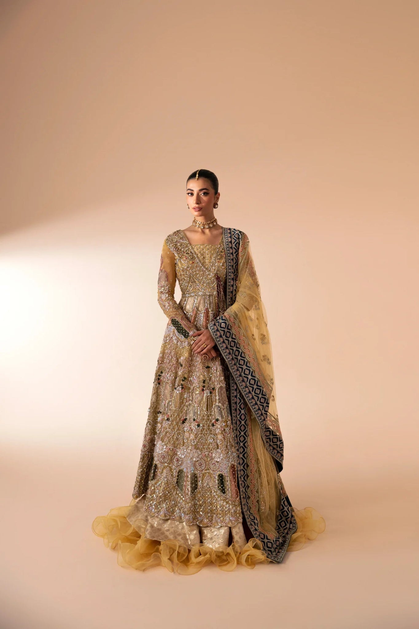 Model wearing Manara from Mysie by Tahira in a gold embellished bridal dress with intricate detailing and multi - colored accents. Pakistani wedding clothes online in UK.