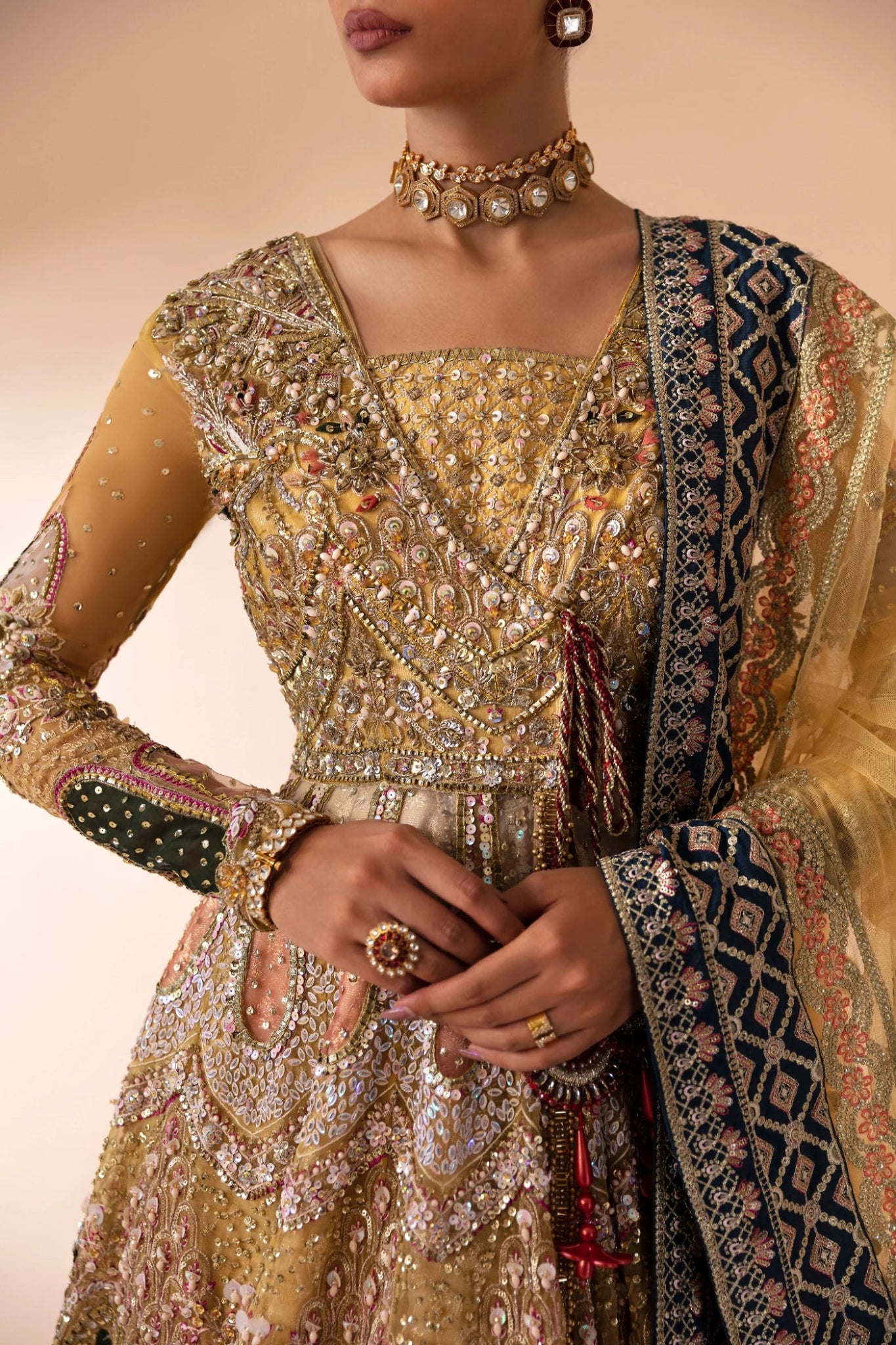 Model wearing Manara from Mysie by Tahira in a gold embellished bridal dress with intricate detailing and multi - colored accents. Pakistani wedding clothes online in UK.