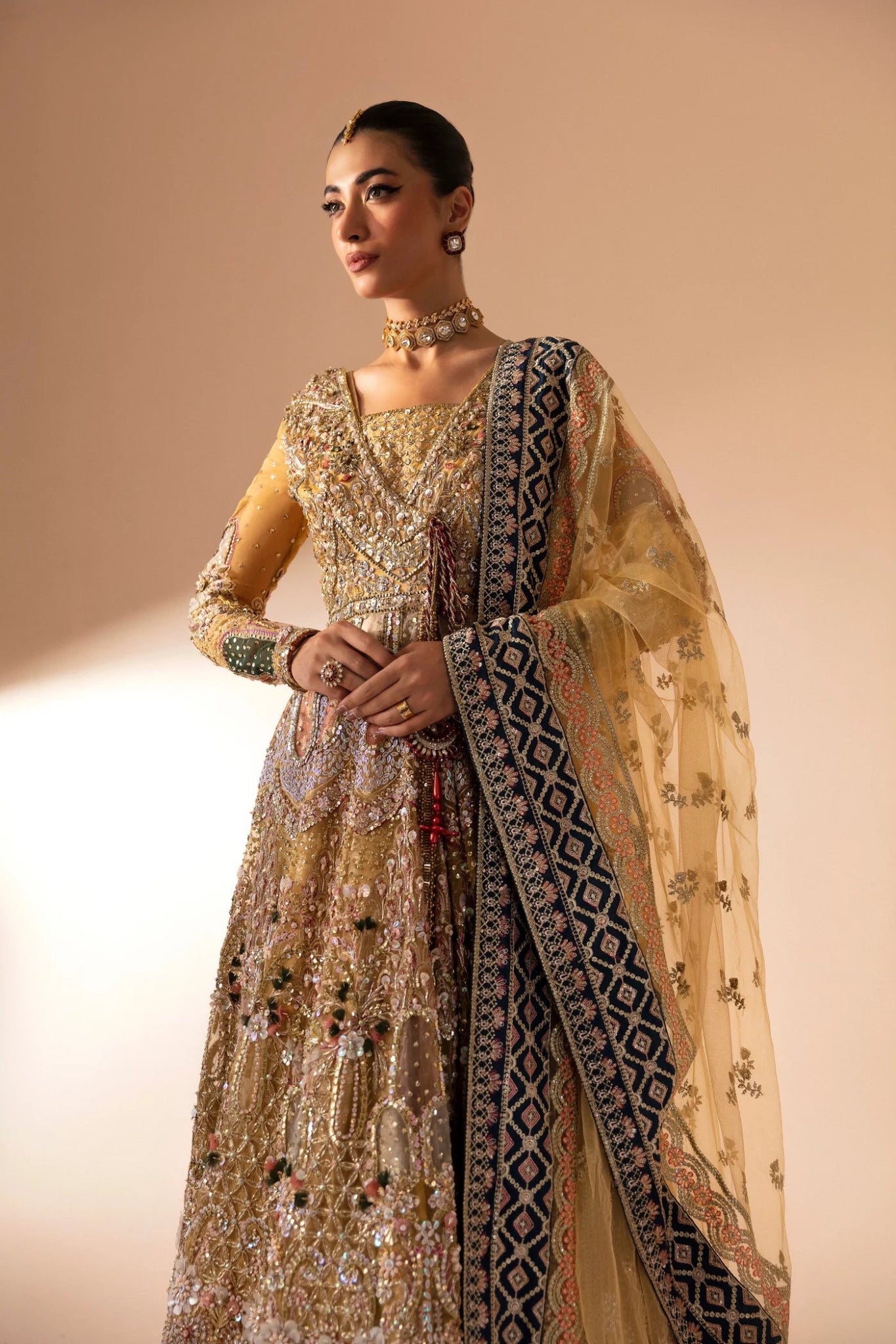 Model wearing Manara from Mysie by Tahira in a gold embellished bridal dress with intricate detailing and multi - colored accents. Pakistani wedding clothes online in UK.