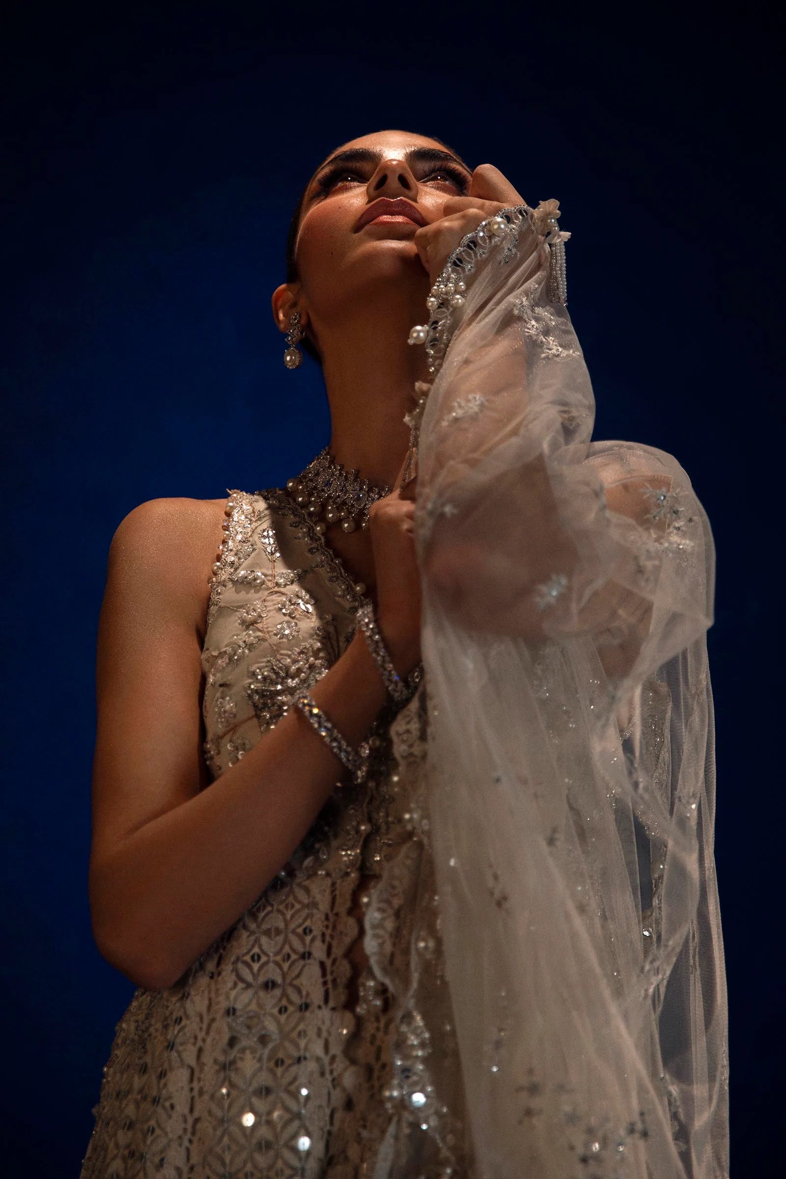 Model in Sana Safinaz silver NURA gown showcasing opulent Pakistani fashion in the UK.