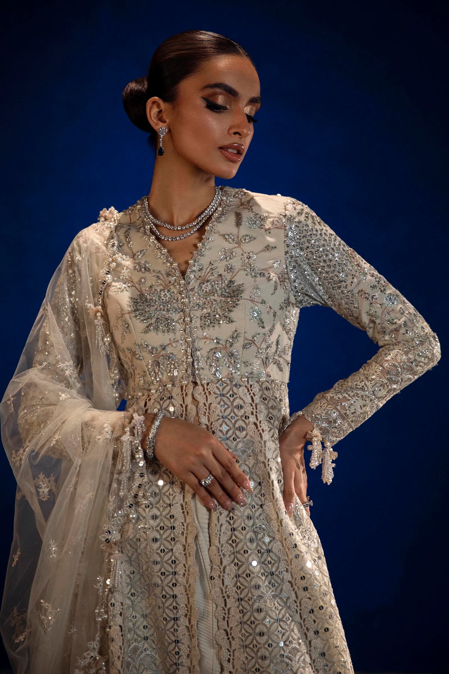 Model in Sana Safinaz silver NURA gown showcasing opulent Pakistani fashion in the UK.