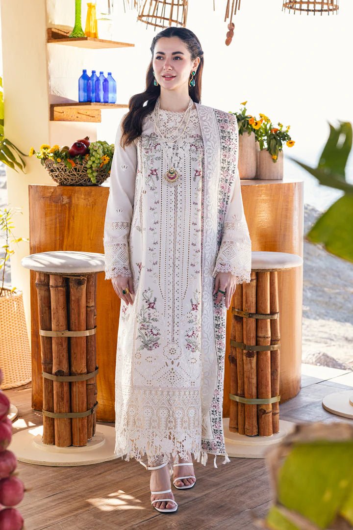 Model wearing a white FP - 12 MARWA dress from Qalamkar with intricate embroidery, standing against a beach background. Pakistani clothes online in UK, lawn suits.