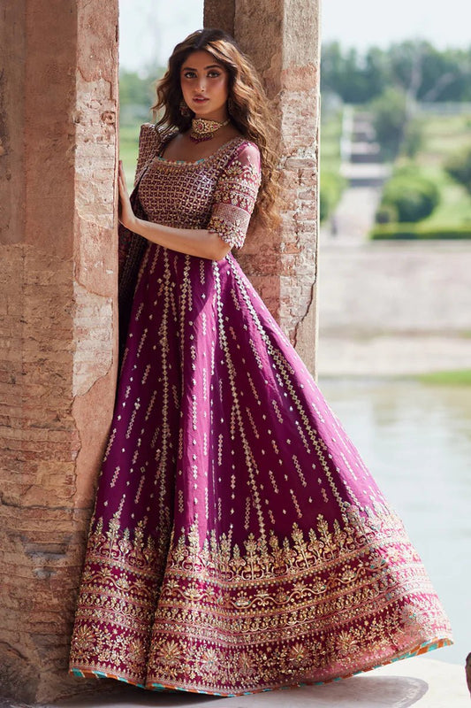 Model wearing Qalamkaar Shadmani Luxury Formals '24 Alya SH - 04 dress in deep magenta with intricate gold embellishments. Shop Pakistani bridal dresses online in the UK now.