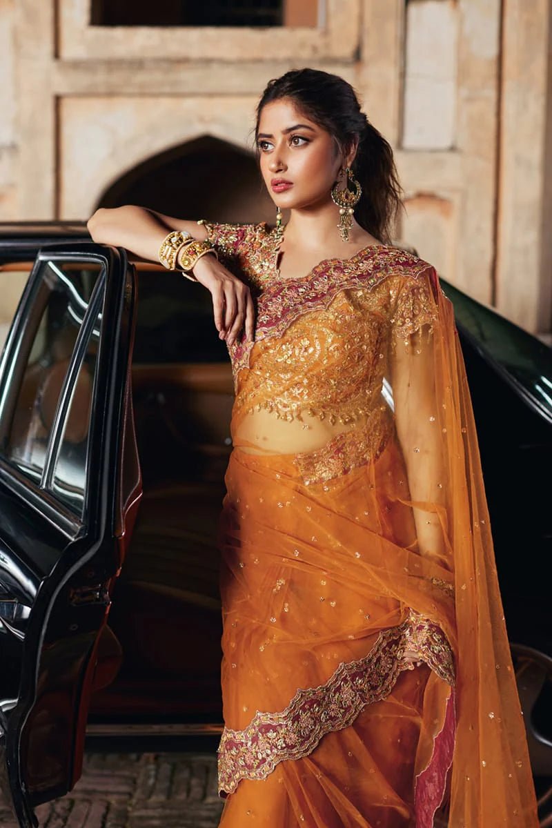 Model wearing Qalamkaar Shadmani Luxury Formals '24 Raniya SH - 02 dress in burnt orange with intricate gold embroidery. Shop Pakistani bridal dresses online in the UK now.