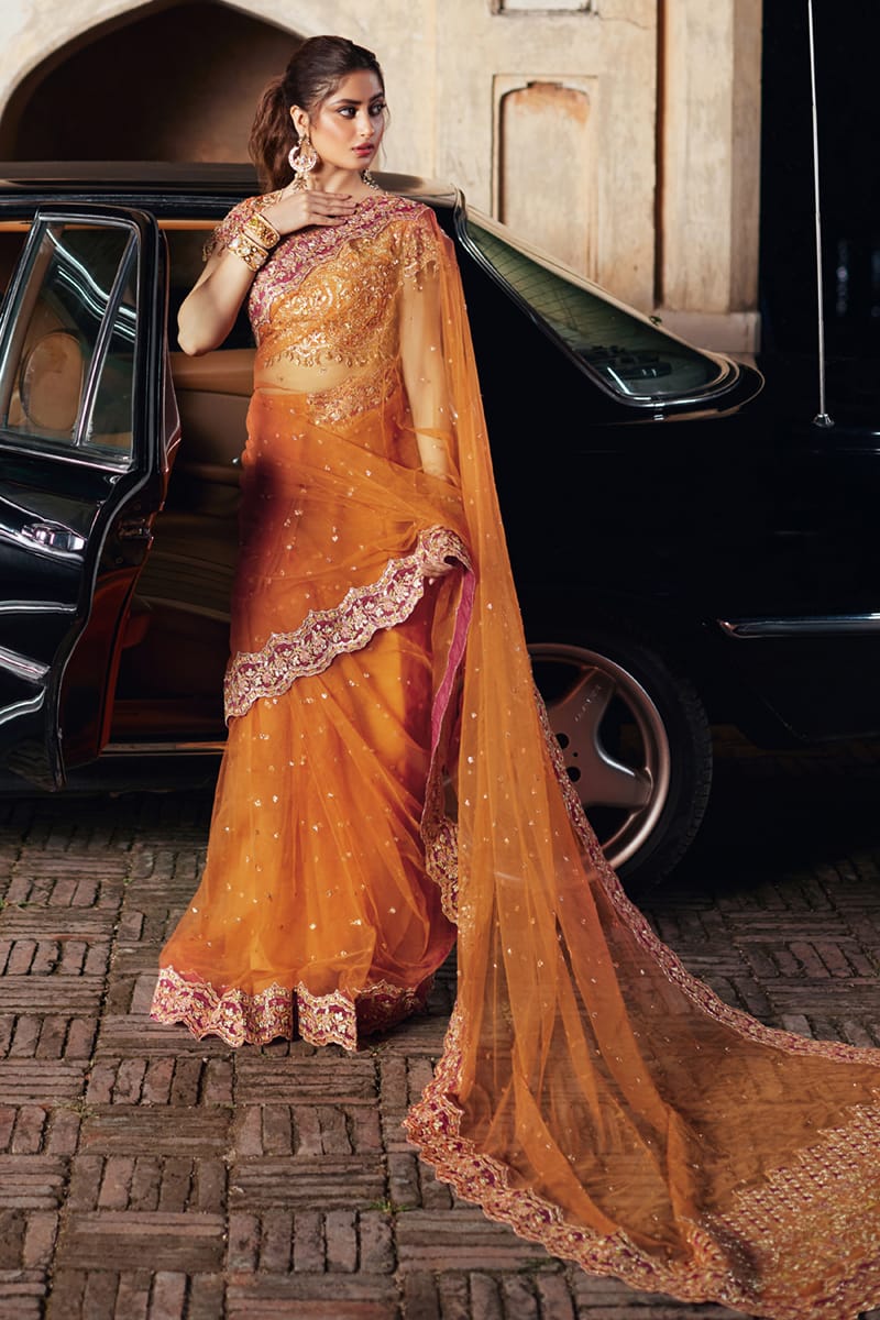 Model wearing Qalamkaar Shadmani Luxury Formals '24 Raniya SH - 02 dress in burnt orange with intricate gold embroidery. Shop Pakistani bridal dresses online in the UK now.