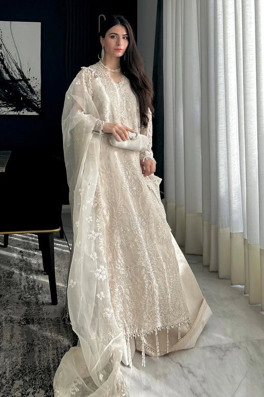 A model wearing an elegant off - white Saad Shiekh ensemble from collection Silsila with intricate organza embroidery, an embroidered dupatta with detailed pallu, and complementing raw silk trousers.