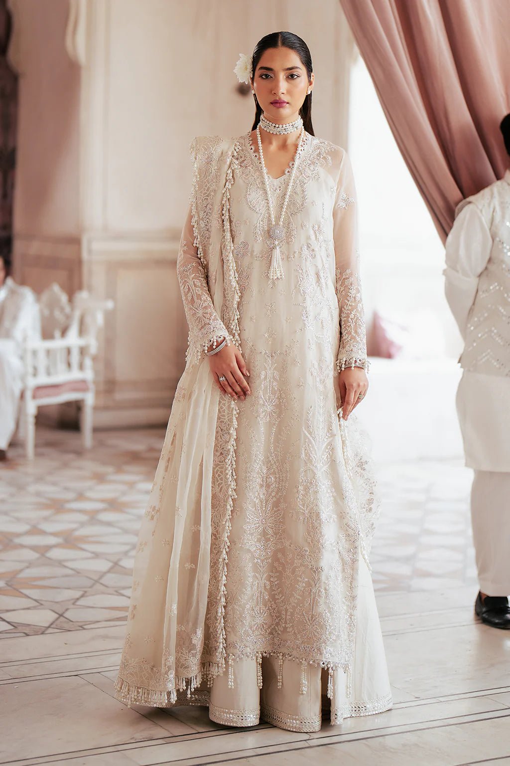 A model wearing an elegant off - white Saad Shiekh ensemble from collection Silsila with intricate organza embroidery, an embroidered dupatta with detailed pallu, and complementing raw silk trousers.