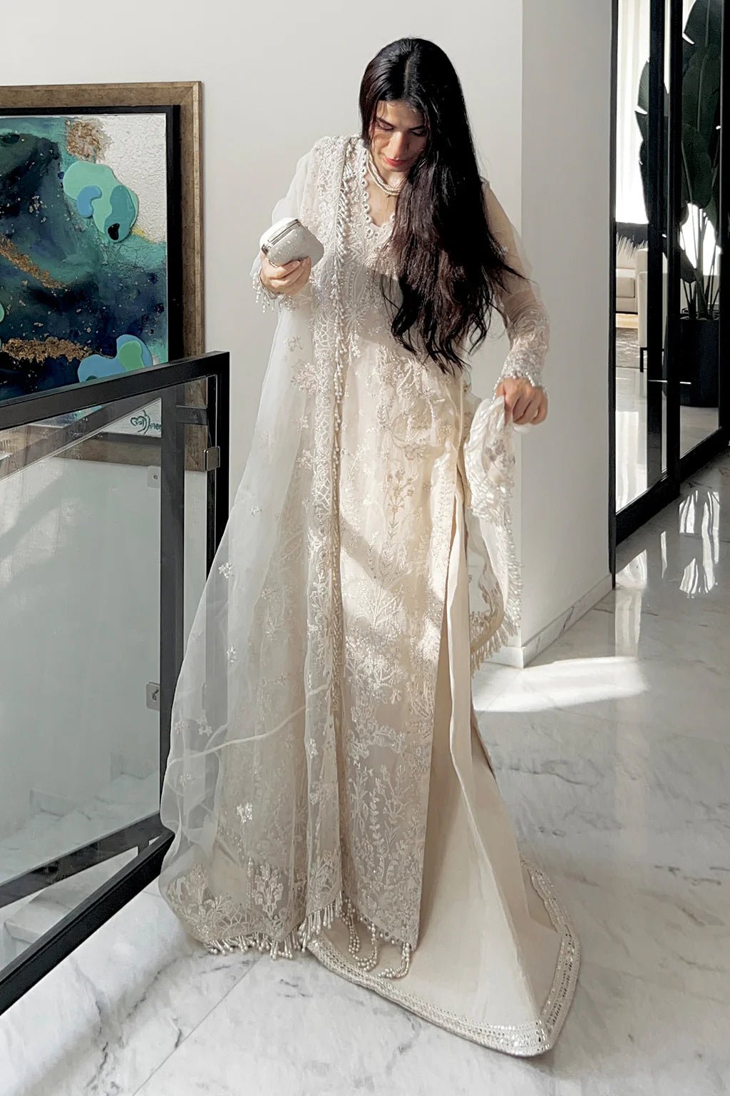 A model wearing an elegant off - white Saad Shiekh ensemble from collection Silsila with intricate organza embroidery, an embroidered dupatta with detailed pallu, and complementing raw silk trousers.