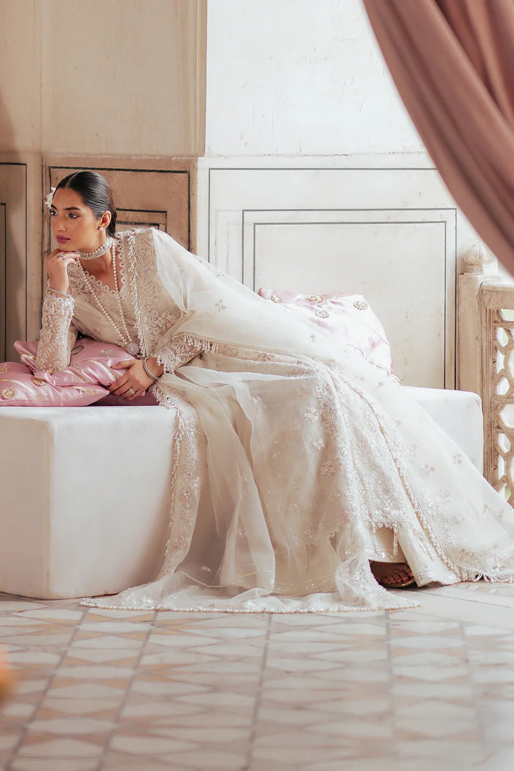 A model wearing an elegant off - white Saad Shiekh ensemble from collection Silsila with intricate organza embroidery, an embroidered dupatta with detailed pallu, and complementing raw silk trousers.