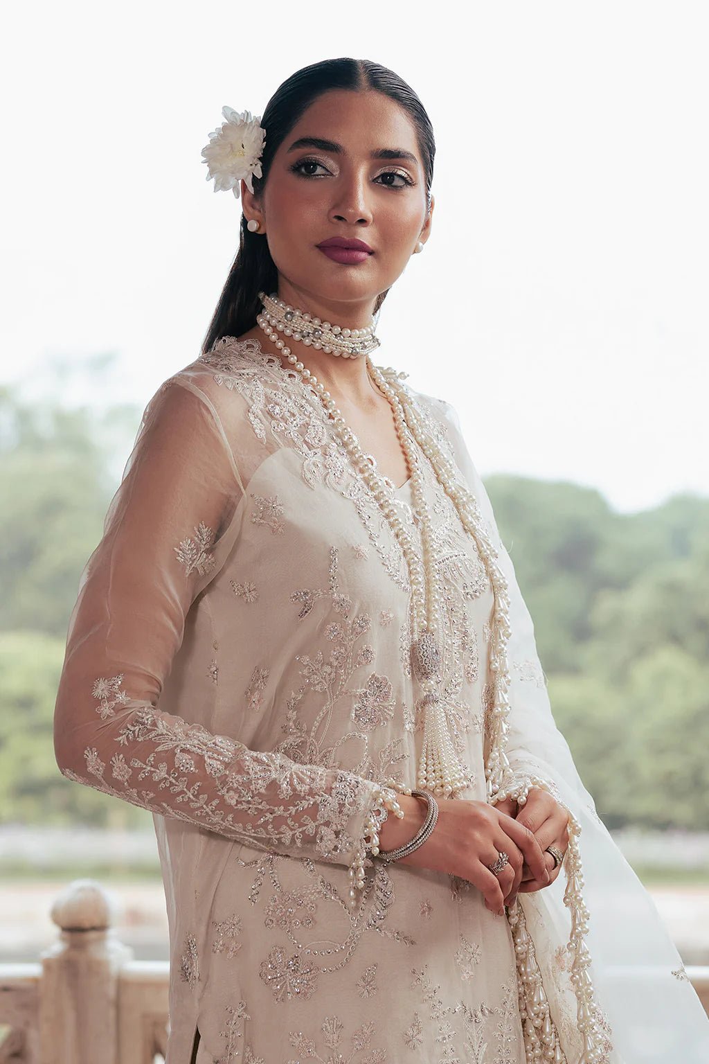 A model wearing an elegant off - white Saad Shiekh ensemble from collection Silsila with intricate organza embroidery, an embroidered dupatta with detailed pallu, and complementing raw silk trousers.