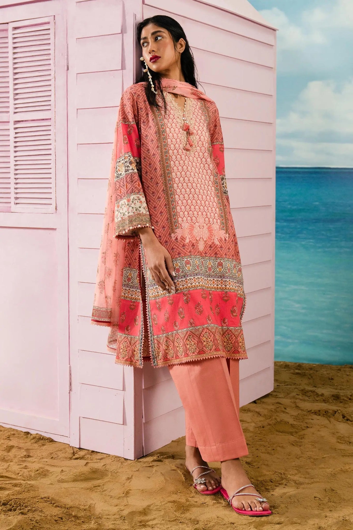 Model wearing Sana Safinaz coral pink lawn suit, elegant Pakistani summer wear in the UK.