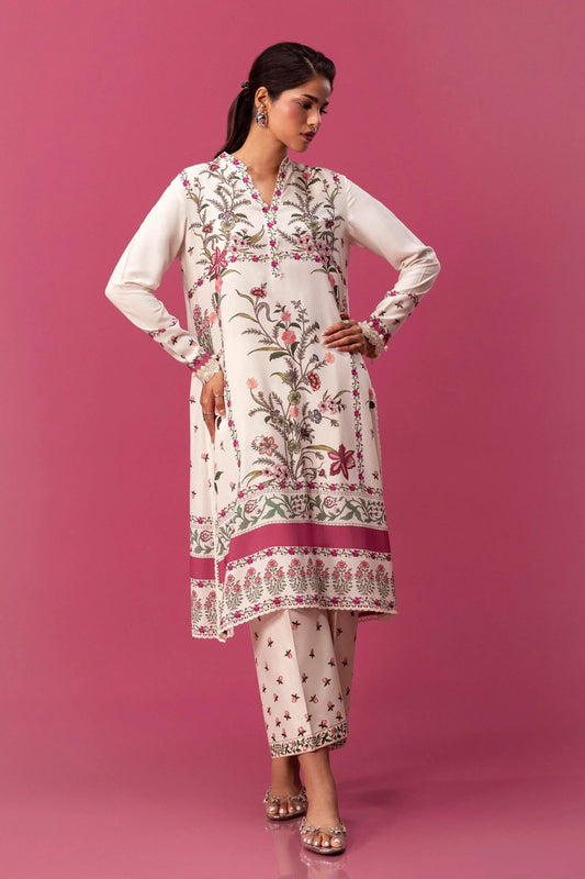 Model wearing a two - piece Sana Safinaz suit from Mahay Winter '24 with floral digital prints on a white linen shirt, embroidered organza patti, and matching cambric pants. Available online in the UK.