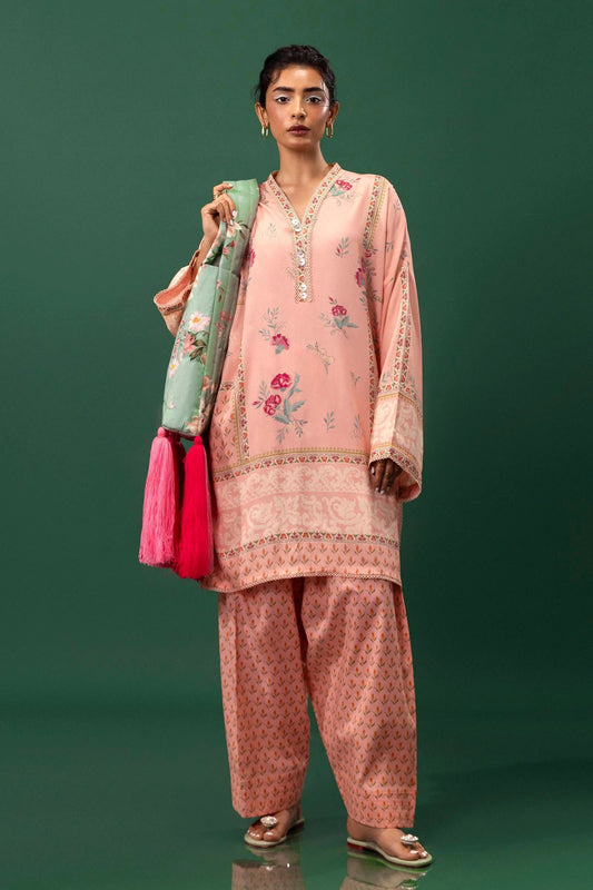 Model wearing a two - piece Sana Safinaz suit from Mahay Winter '24 in peach, featuring floral digital prints, embroidered organza patti, and matching cambric pants. Available online in the UK.