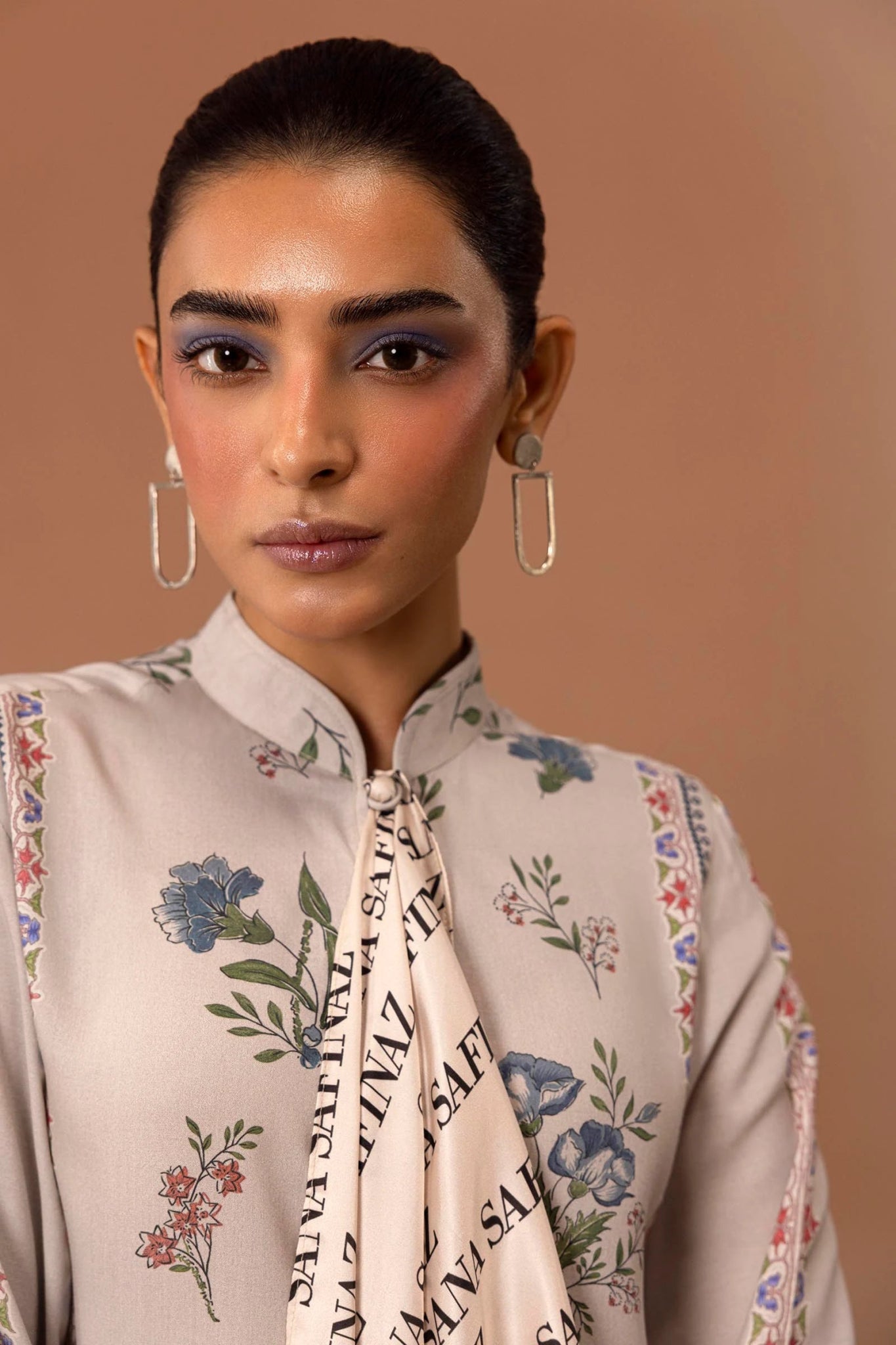 Model wearing a two - piece Sana Safinaz suit from Mahay Winter '24 in beige, featuring floral digital prints, embroidered organza patti, and printed cambric pants. Available online in the UK.