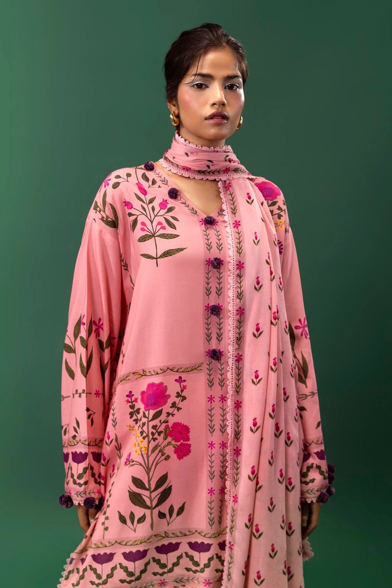 Model wearing a three - piece Sana Safinaz suit from Mahay Winter '24 in pink, featuring digital prints on linen, a printed dupatta, and dyed cambric pants. Available online in the UK