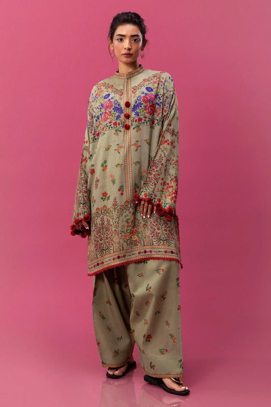 Model wearing a two - piece Sana Safinaz suit from Mahay Winter '24 in olive green, featuring intricate floral digital prints on a linen shirt and matching cambric pants. Available online in the UK.