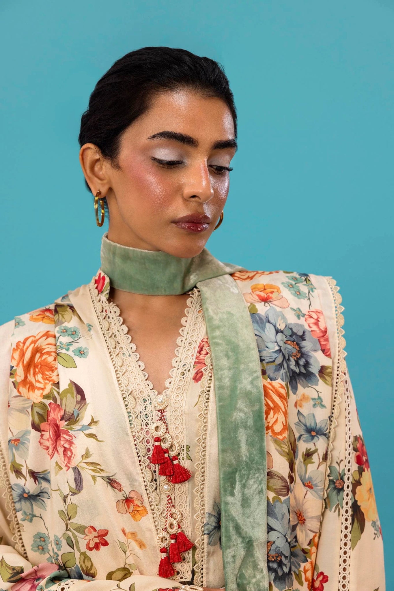 Model wearing a three - piece Sana Safinaz suit from Mahay Winter '24 featuring a cream linen shirt with vibrant floral prints, a matching printed dupatta, and striped cambric pants. Available online in the UK.