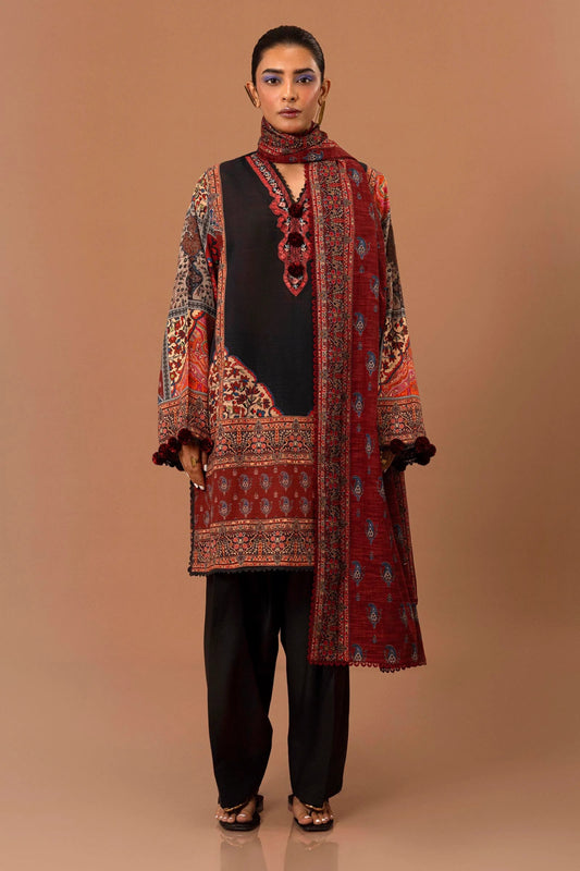 Model wearing a two - piece Sana Safinaz suit from Mahay Winter '24 featuring a black and red digital printed slub shirt with an embroidered organza neckline, paired with a coordinating khaddar dupatta. Available online in the UK.