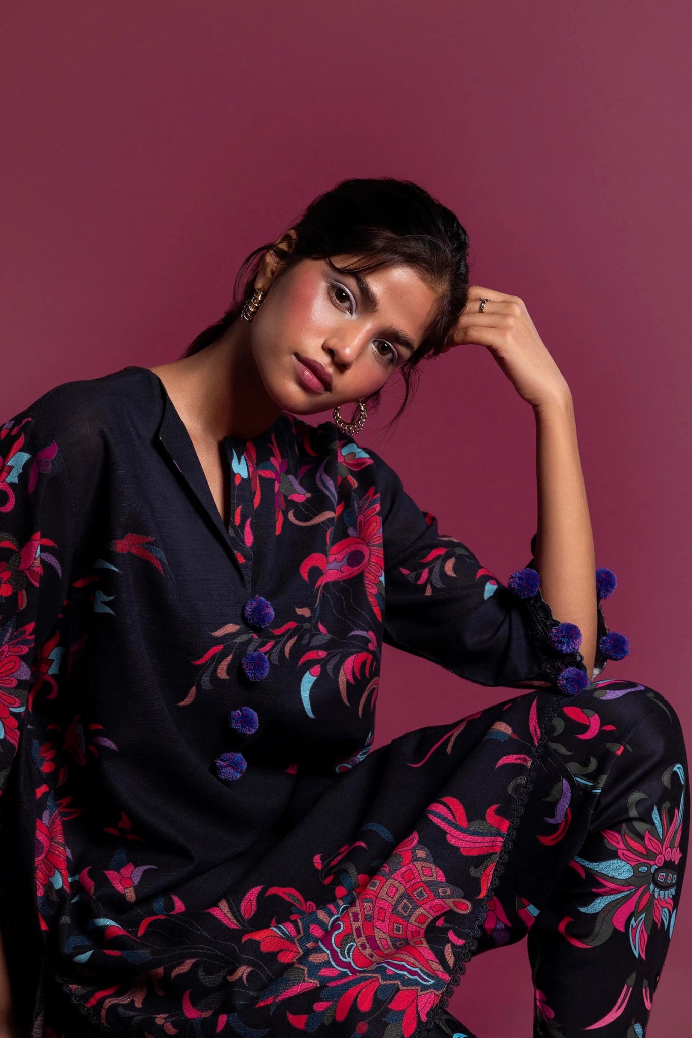 Model wearing a two - piece Sana Safinaz outfit from the Mahay Winter '24 collection, featuring a digitally printed slub shirt with vibrant floral motifs and embroidered details on the sleeves. The ensemble is paired with matching cambric pants, creating a stylish and coordinated look. Available online in the UK.